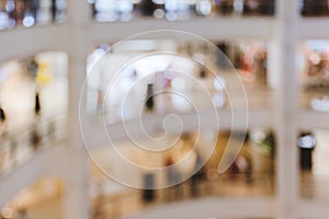 Blurred image, shallow depth of focus - interior of large multi-story shopping center with warm light, people.