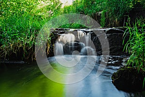 Blurred image of a small river waterfall close-up.