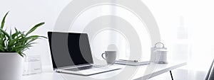 Blurred laptop with blank screen on white office desk. Panoramic banner