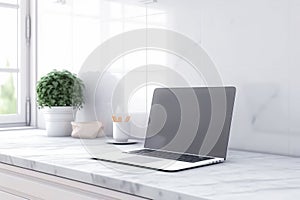 Blurred laptop on a white marble table in a bright room with a large window. mock up