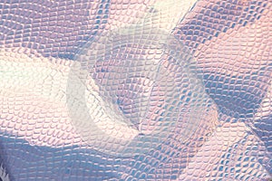 Blurred light rainbow crumpled holographic background with a reptile skin texture in blue toned