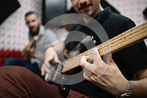 Blurred male guitarists playing guitars in studio