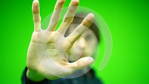 Blurred man 20s showing stop gesture with palm isolated on green screen background in studio