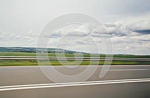 Blurred motion blur photo of autobahn railroad . Huge big white white clouds above