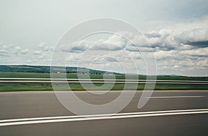 Blurred motion blur photo of autobahn railroad . Huge white clouds above