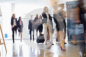 Blurred motion of business people with luggage walking at convention center