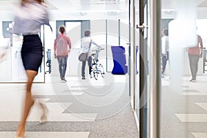 Blurred motion of businesswoman walking with male colleagues in background at office