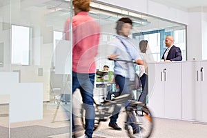 Blurred motion of colleagues with business people discussing in background at office