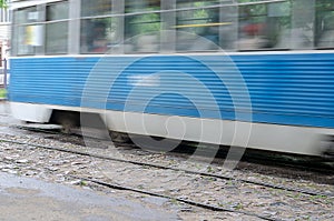 Blurred motion of the defocused blue tram on the streets of the city.