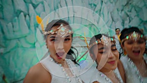 Blurred motion of four joyful dancers in white costumes with headpieces, performing with expressive gestures