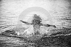 Blurred motion silhouette of happy kid playing in the sea. Child having fun on ocean outdoors. Summer vacation and