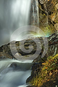 Blurred motion of a waterfall with a rainbow in mist.