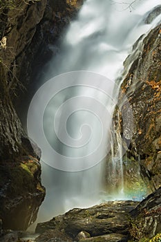 Blurred motion of a waterfall with a rainbow in mist.