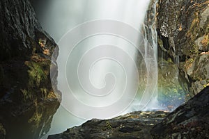 Blurred motion of a waterfall with a rainbow in mist.