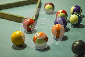 A blurred multicolored billiard balls on a blue table cloth with shadows and a triangle. numbers on billiard balls