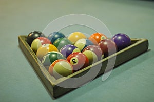 A blurred multicolored billiard balls on a blue table cloth in a wooden triangle. numbers on billiard balls