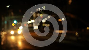 Blurred night footage of city street with moving car lights approaching. Colorful bokeh background