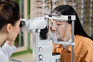 blurred optometrist testing eyesight of asian