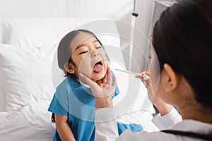 blurred pediatrician holding tongue depressor near