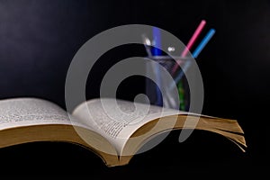 A blurred pen stand with opened book in the foreground -Teaching concept