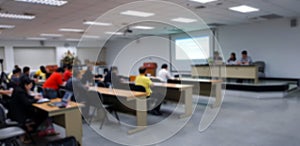 Blurred of people training in room with three instructors, listener and projector.