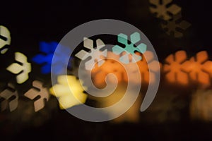 Blurred photo of defocused bokeh colorful lights in the shape of snowflake