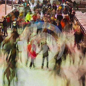 Blurred photo of many persons skating on the ice rink in evening time outdoors , park on winter. Christmas, sport