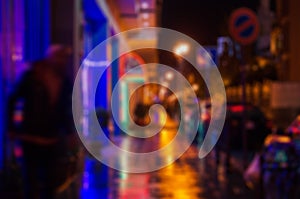 Blurred photo of a night city street, wet asphalt, reflection of shop windows