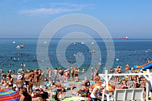 Blurred photo. Summer beach by the sea with many people having a rest on the beach.