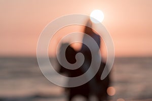 Blurred photo. Woman in summer clothes enjoys riding a horse on a beautiful sandy beach at sunset. Selective focus