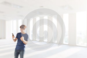 Blurred picture of Happy young man holding smartphone and celebrating his success at e blurred background.