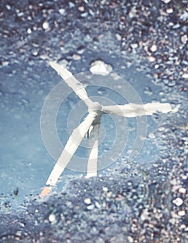 Blurred picture of a windmill turbine reflection in a puddle, abstract conceptual background