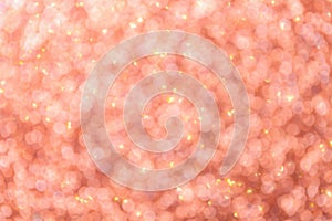 Blurred pink background with circle sparkling lights. Shiny coral glittery bokeh of christmas garland.