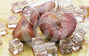 Blurred of Plumcot fruit with red and juicy pulp wet from red wine and ice cubes