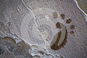 A blurred print of a foot on a frozen stone wall close-up