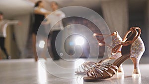 Blurred professional man and woman dancing Latin dance in costumes in the Studio, ballroom shoes in the foreground