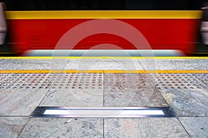 Blurred red subway train in Warsaw Poland, tactile paving for vi