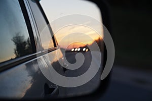 Blurred road and sunset in car rearview mirror
