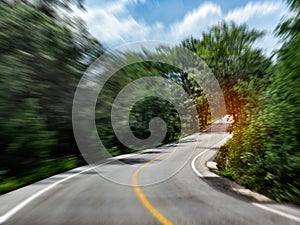 Blurred road surrounded with green rainforest in summertimes