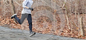 Blurred runner showing speed running downhill on a dirt path in the woods