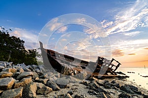 Silhouette image of abandon shipwrecked on rocky shoreline. dark cloud and soft on water photo