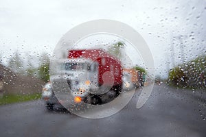 Blurred semi truck convoy in rain drops and headlight on road photo