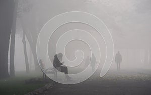 Blurred shadows of people in the fog on the alley