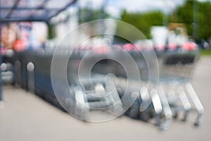 Blurred shopping carts in 2 rows stand under a rectangular glass roof. photo
