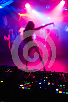 Blurred silhouette of slender girl dancer on nightclub scene on bright colored background