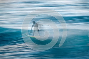 Blurred silhouette of a surfer on a wave. Concept of movement and speed