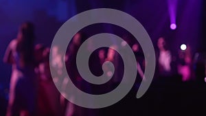 Blurred silhouettes of people dancing in a nightclub on the dance floor at a music concert to electronic music with slow