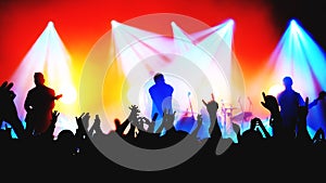 blurred silhouettes of rock band musicians on stage and crowd at a concert