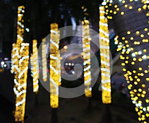 Blurred small yellow gold christmas light bulbs hanging and wrap around coconut trees