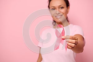 Blurred smiling African woman in pink t-shirt holding satin ribbon in her hand. Breast and abdominal cancer awareness, October